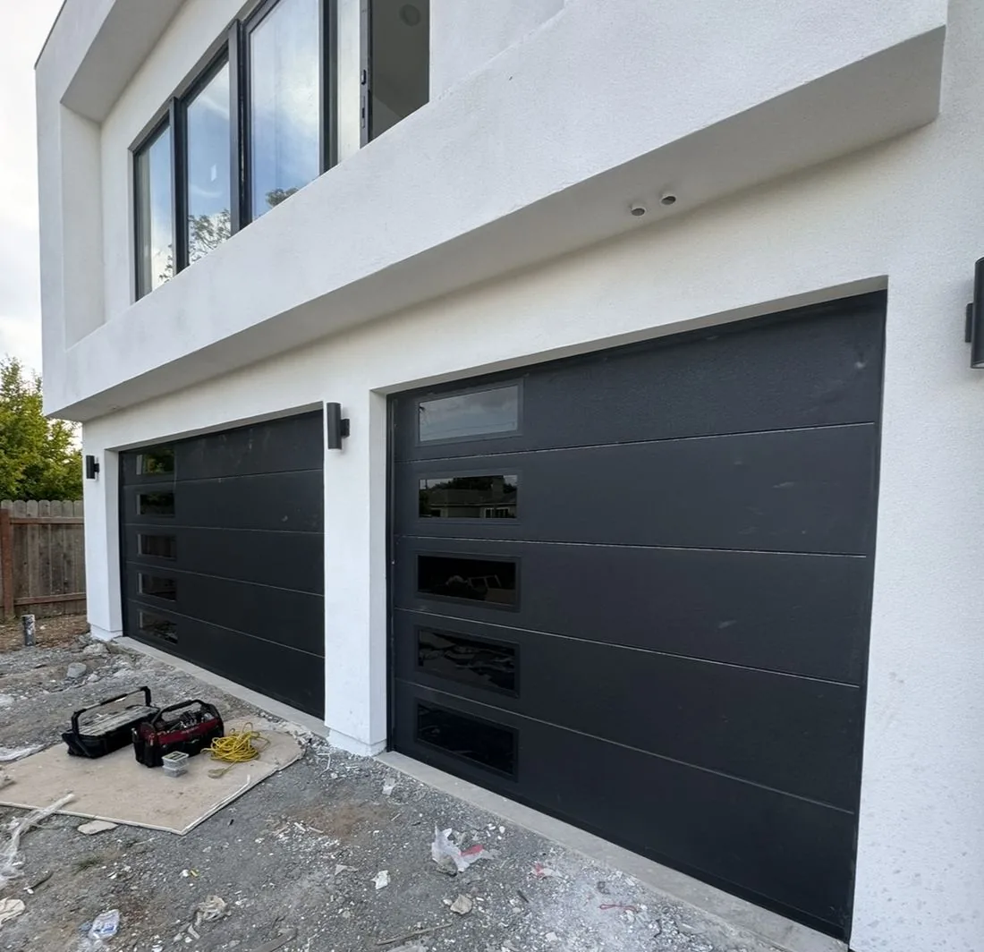Two new black flush-panel garage doors on a new build