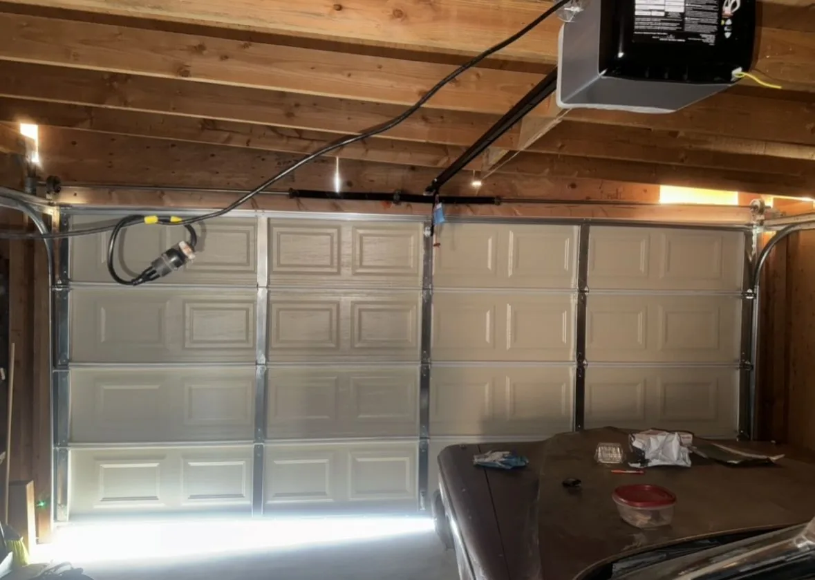 New white sectional garage door and opener installed in a wood-beam garage